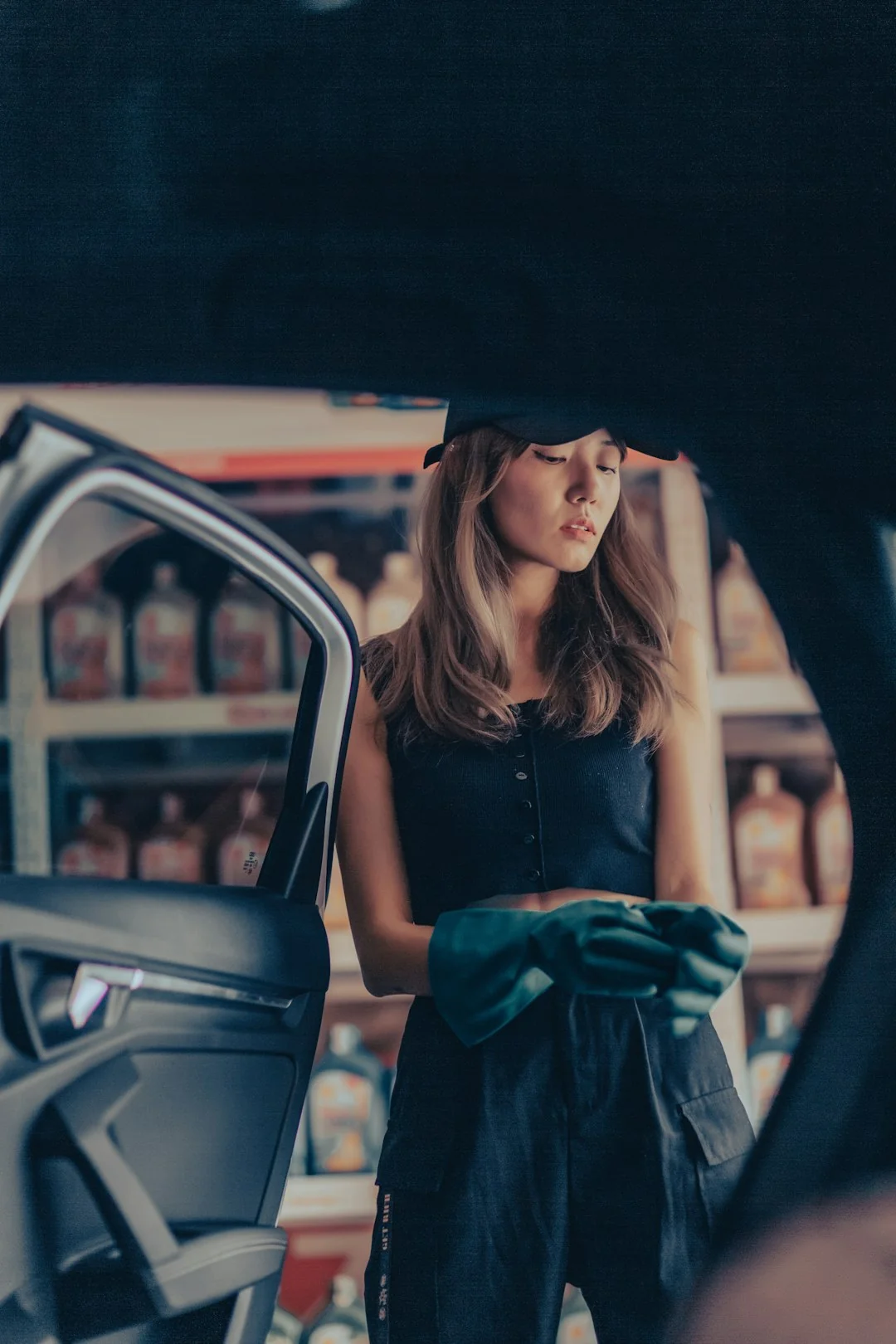 Vue de côté d’une jeune femme concentrée, portant des gants en latex, debout et nettoyant un miroir dans une pièce lumineuse en journée